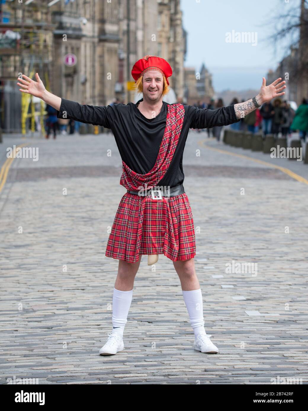 Edinburgh, UK. 13th Mar, 2020. Pictured: Man seen on the Royal Mile in Edinburgh wearing a tartan kilt, tartan plaid and red hat, strutting his stuff for the camera. Credit: Colin Fisher/Alamy Live News Stock Photo