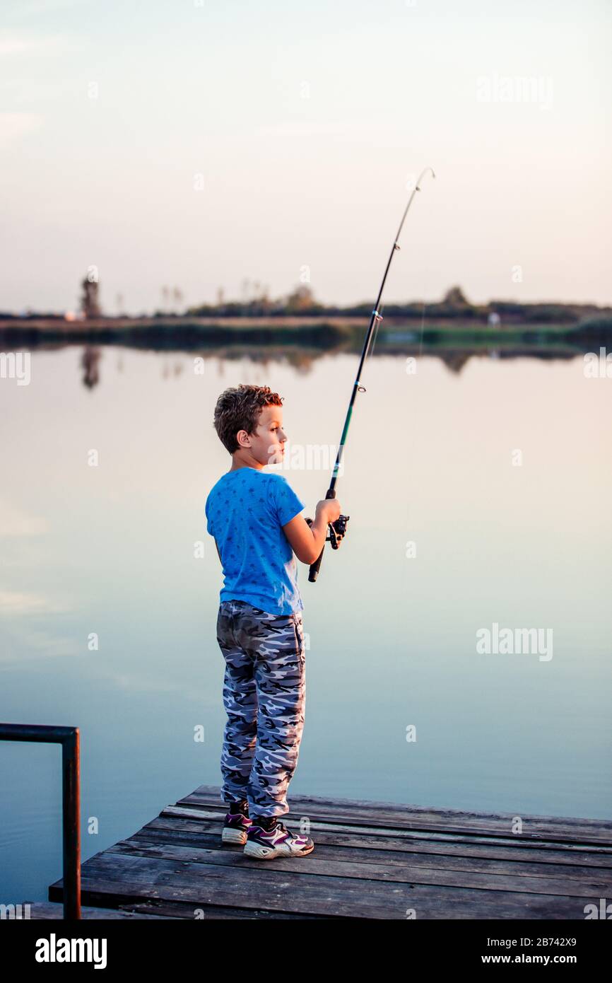 Little happy boy with a fishing rod. Cute child fishing on a lake in a