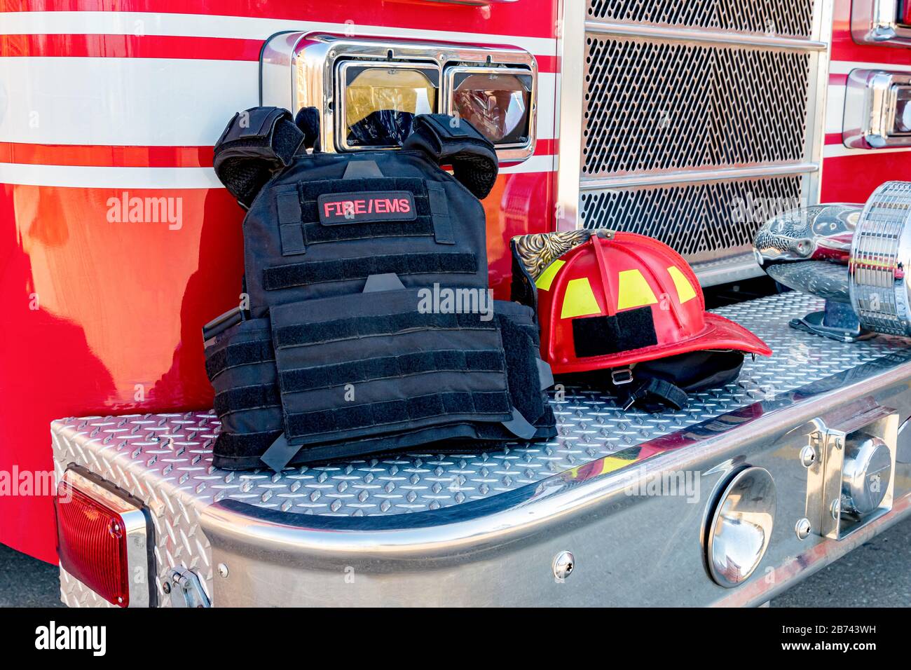 ballistic vest and red firefighter helmet on fire truck bumper. Concept of mass casualty shooting, terrorism response of fire department Stock Photo