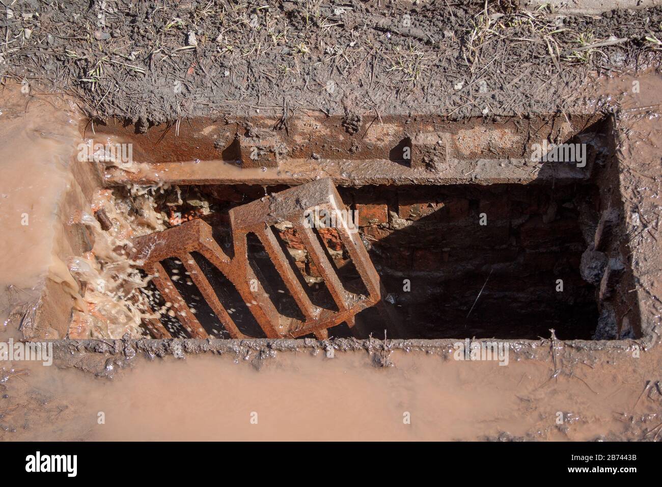 Broken storm drain. Dirty water after the rain and garbage get into the gutter. Environmental pollution. Stock Photo