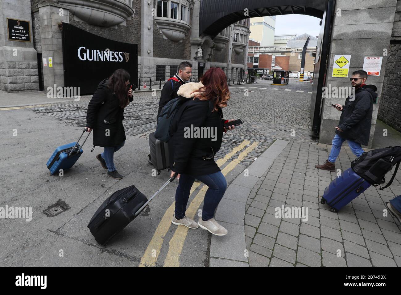 Tourists pass the entrance to the Guinness Storehouse, Dublin, which has been closed to visitors, in line with government recommendations, to help prevent the spread of coronavirus. Stock Photo