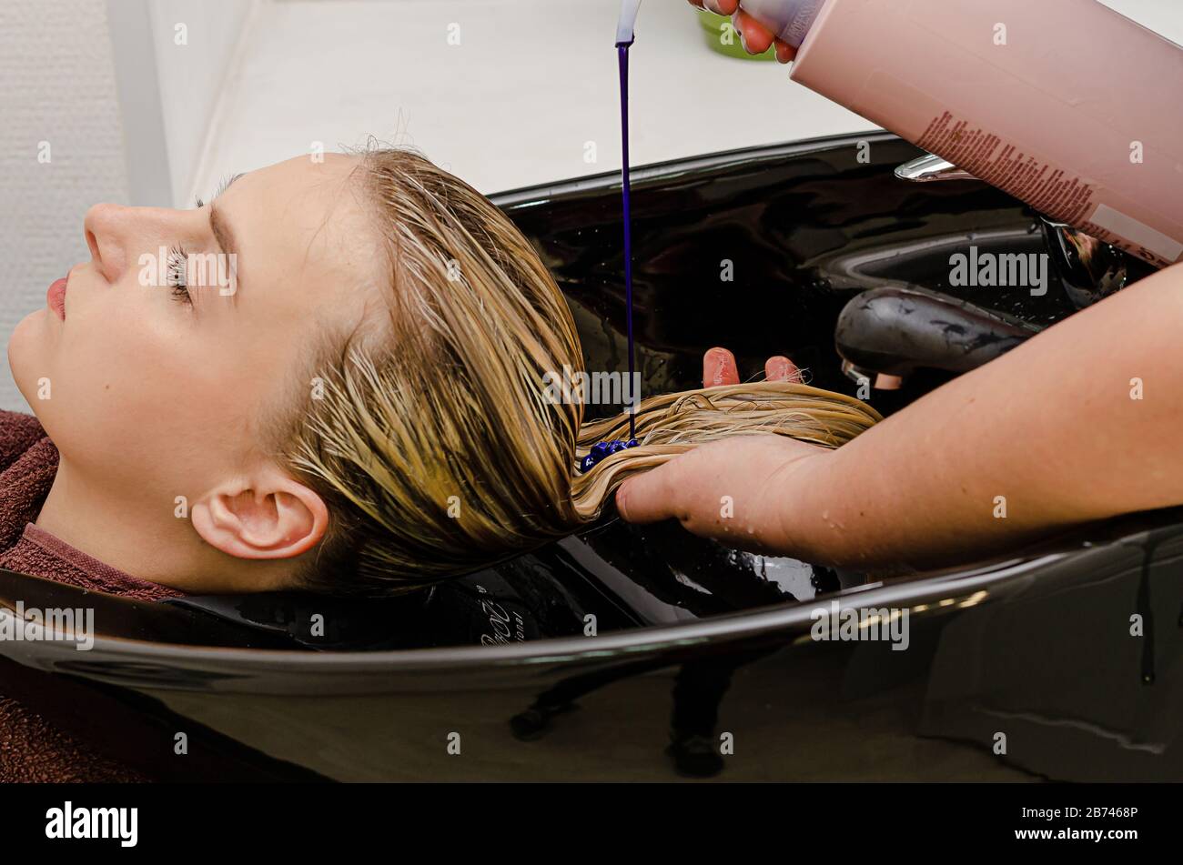 Hair stylist applying coloring purple shampoo after hair dyeing Stock Photo Alamy