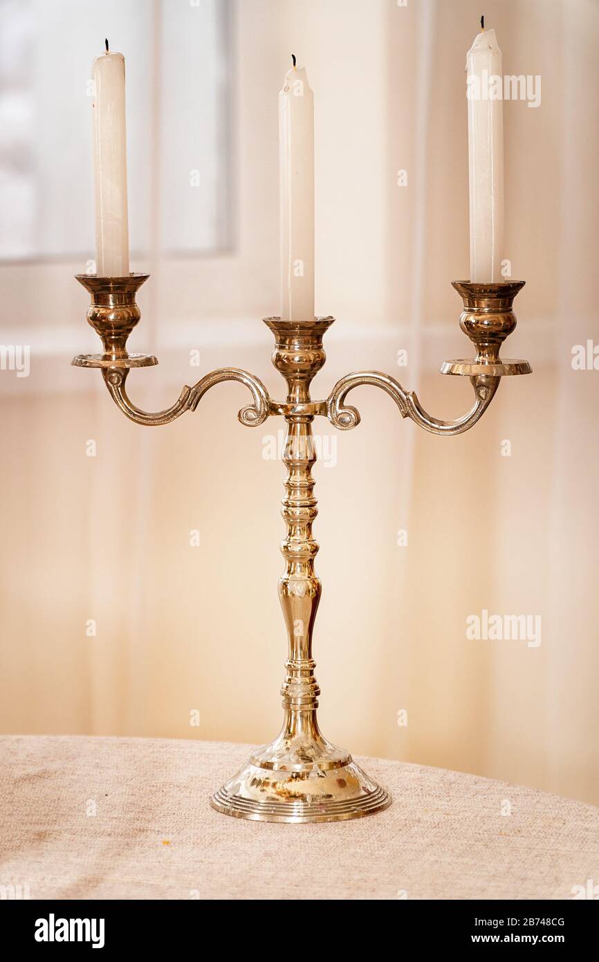Antique gold candlestick with three candles on a light background Stock