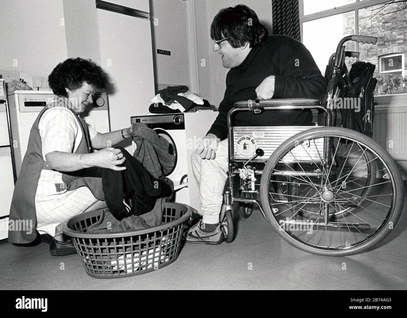 Disabled man at home with carer, UK 1989 Stock Photo