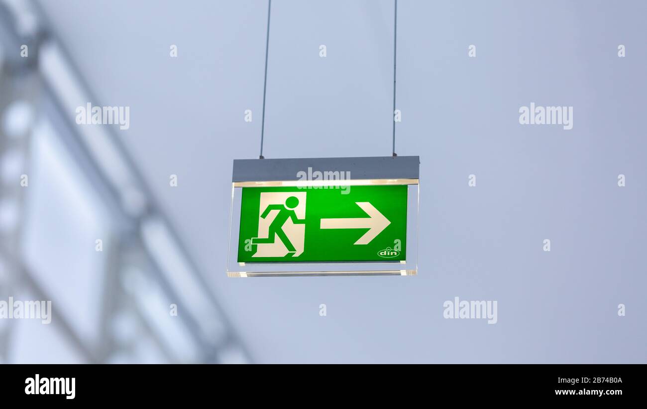View on illuminated emergency exit sign. With running figure and arrow to the right. Neutral, white background. Modern design. Stock Photo
