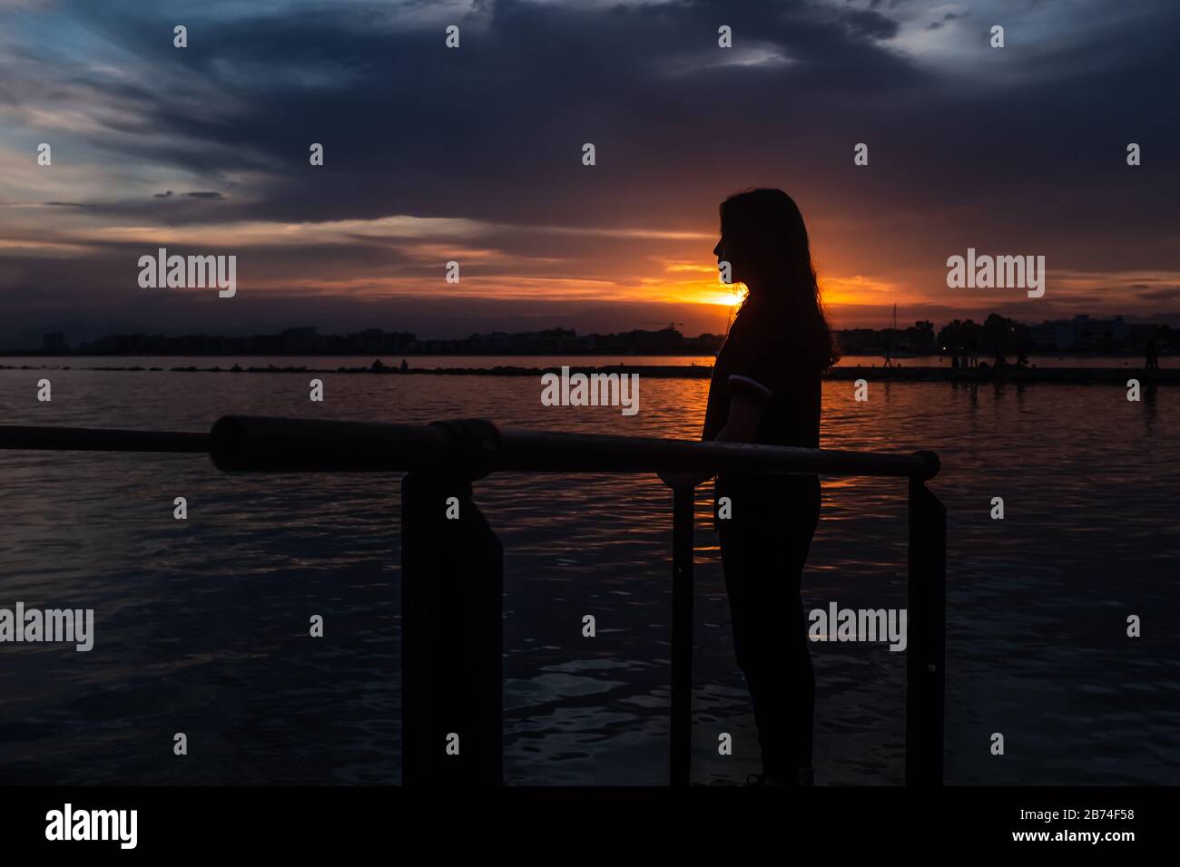 Young teenage girl with long hair at sunset beach looking in the distance. Concepts of introspection and contemplation. Stock Photo
