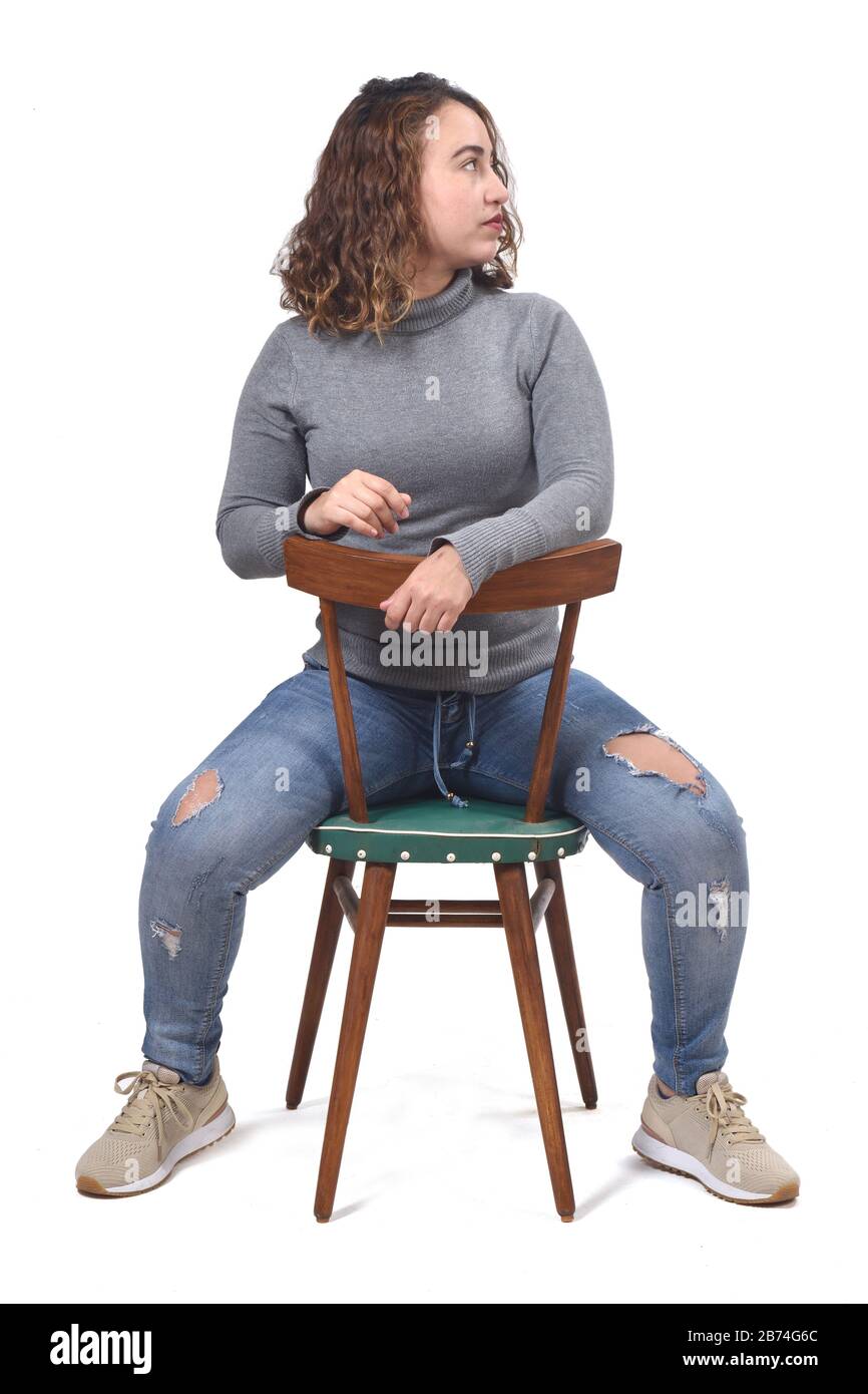 portrait of a woman sitting on a chair in white background, rear view of the chair and look side Stock Photo