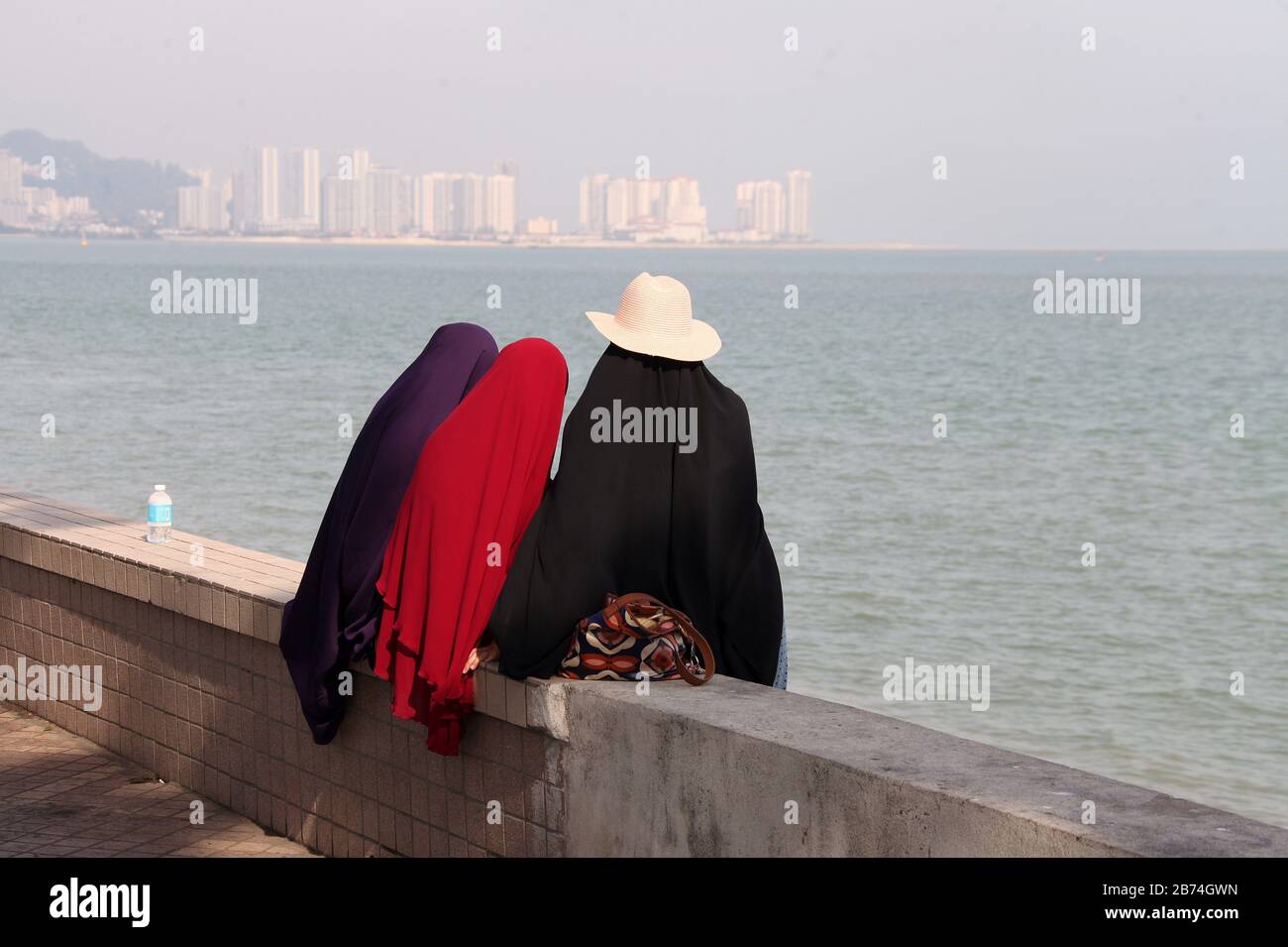 Young Muslim girls sitting by the sea at George Town on Penang Island Stock Photo