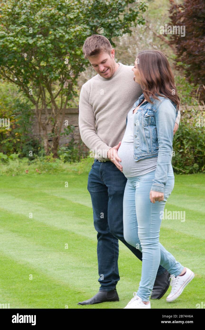 Pregnant young woman walking with her partner, feeling her tummy Stock Photo