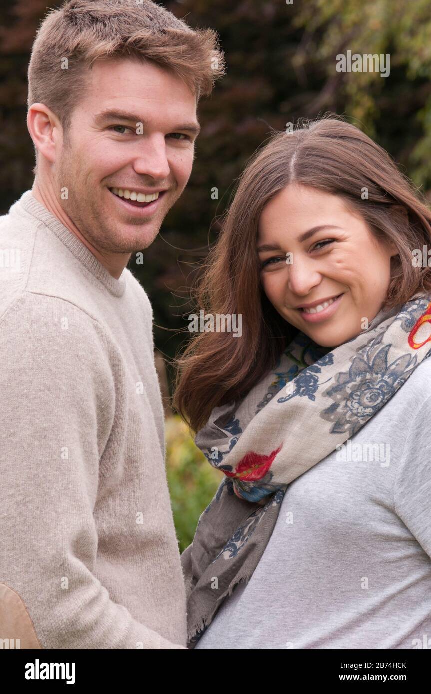 Young happy pregnant woman standing with her partner caressing her tummy Stock Photo