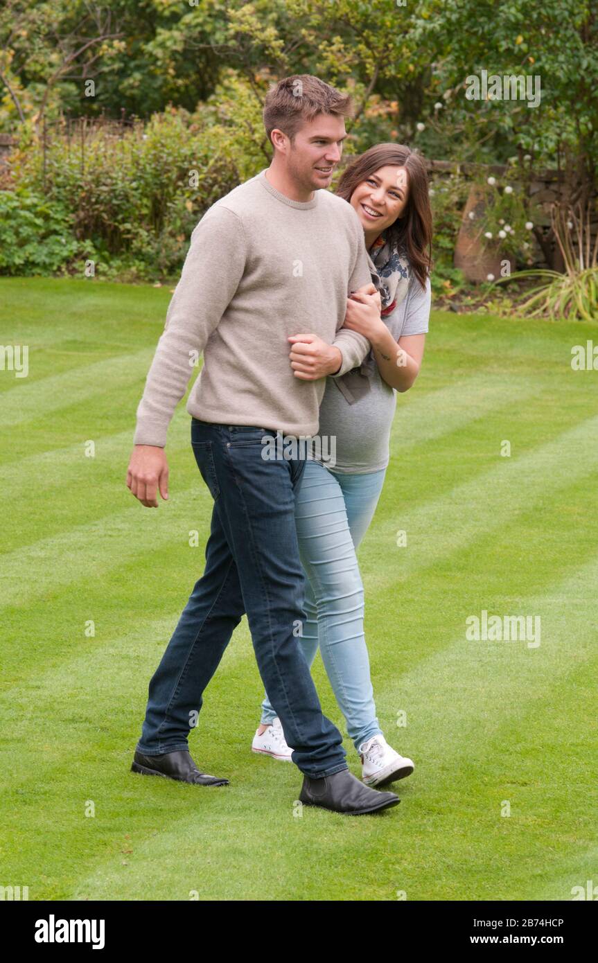 Pregnant young woman walking with her partner arm in arm Stock Photo