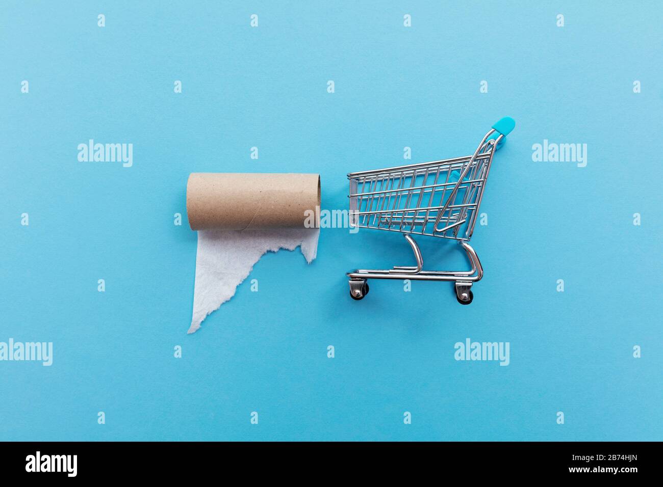Shopping cart with an empty toilet roll on a blue background Stock Photo