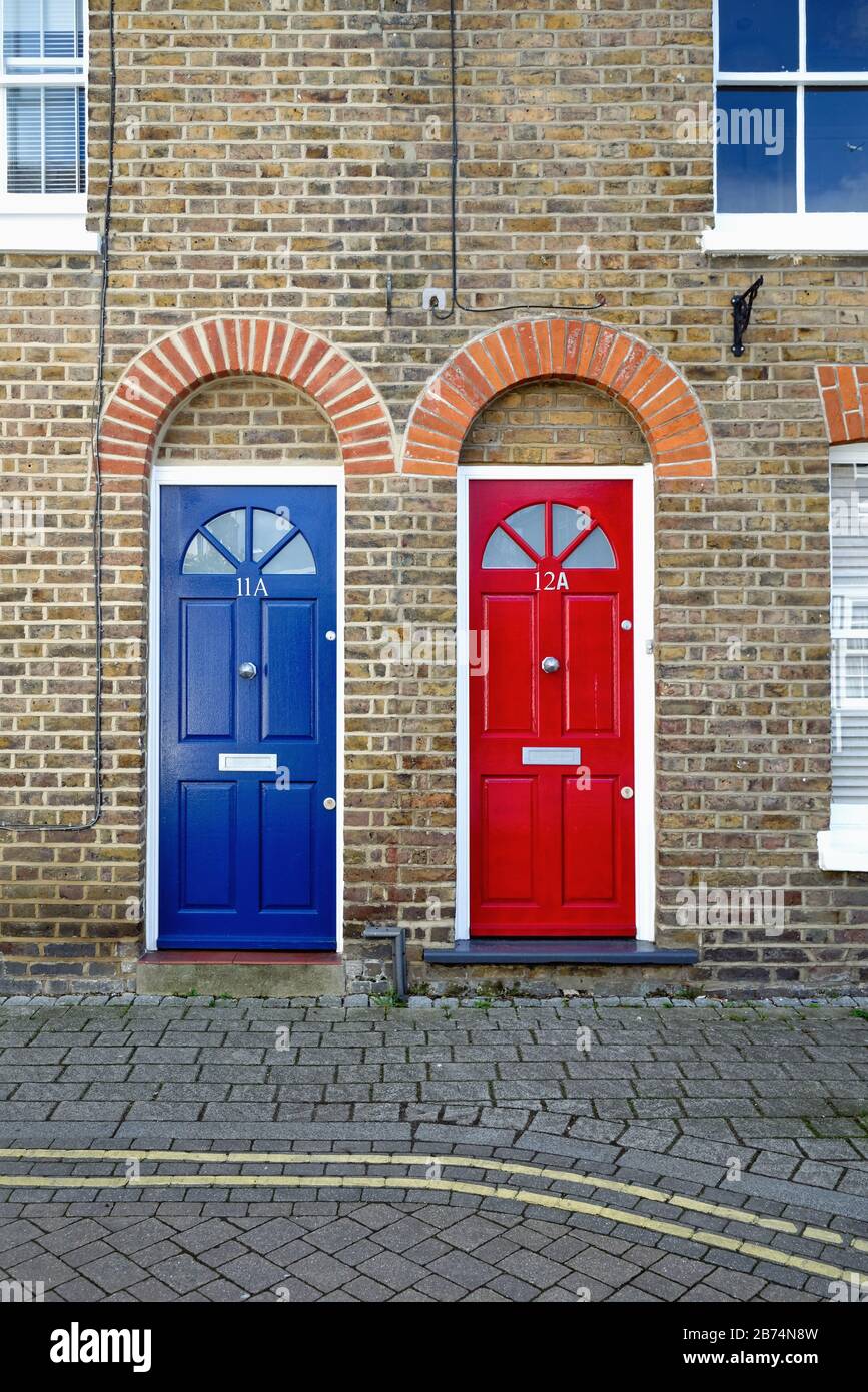 Two identical front doors, one red one blue, on old terraced houses on