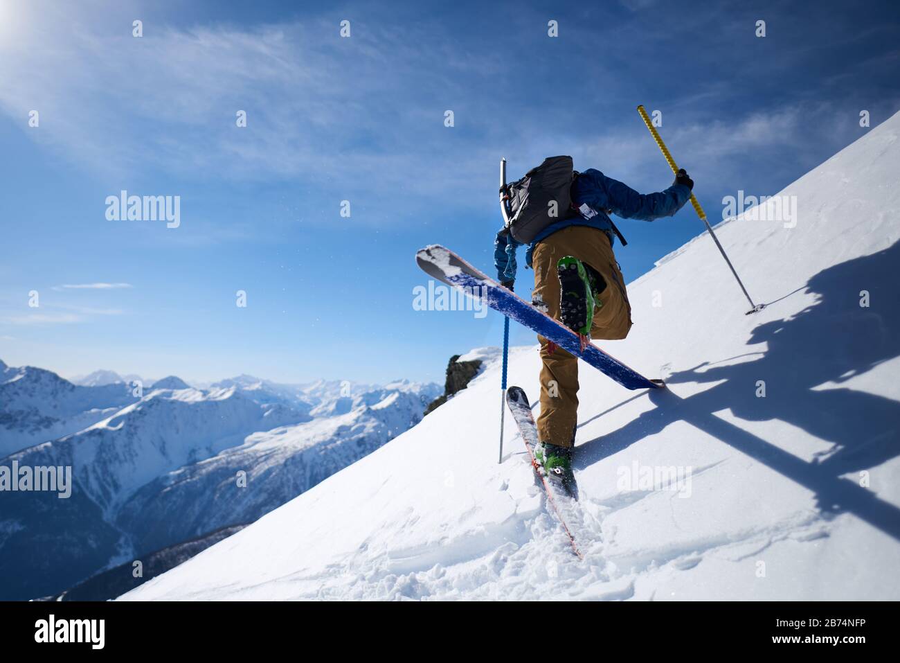 Ski tourer doing an uphill kick turn with mountain backdrop Stock Photo