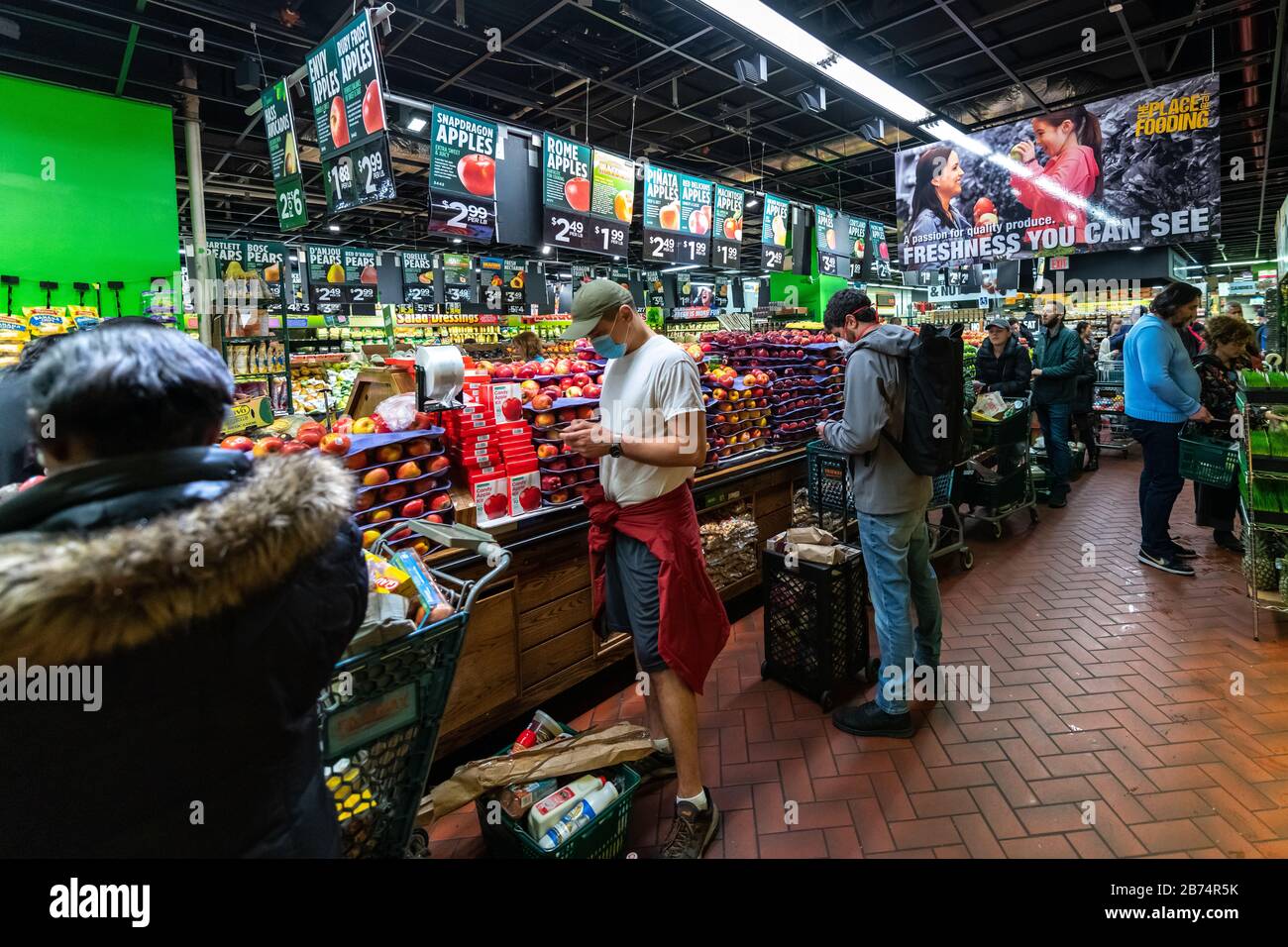 New York, USA. 13th Mar, 2020. Shoppers wear face masks as they wait in line - up to one hour- to pay for their groceries in a New York City supermarket. Crowds went shopping after the city declared emergency to curb the spread of coronavirus. Credit: Enrique Shore/Alamy Live News Stock Photo