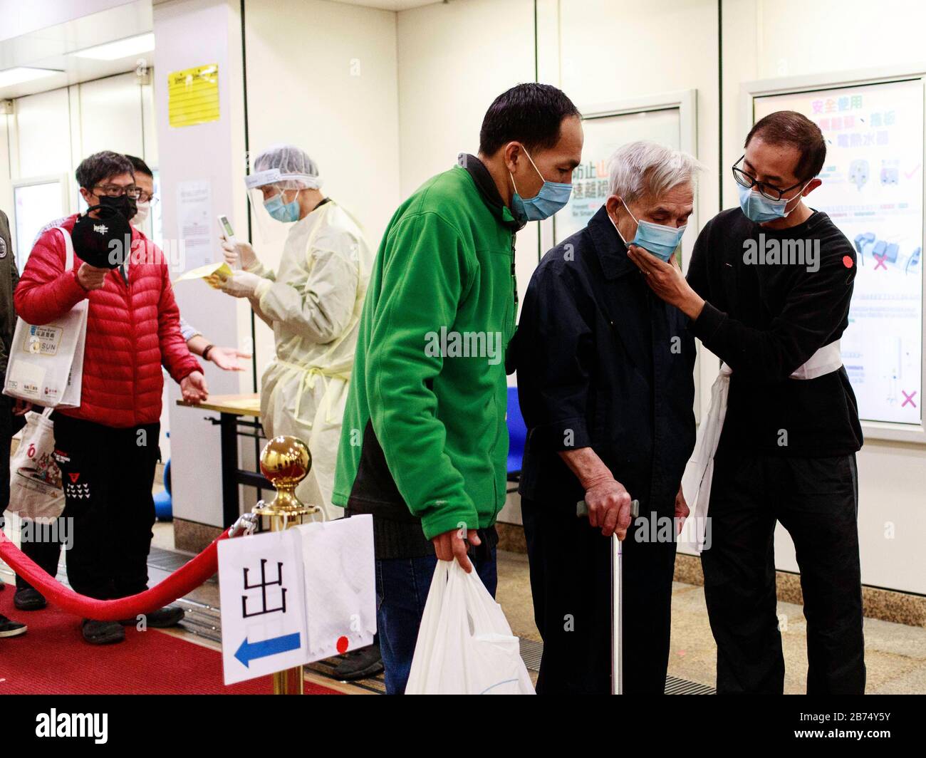 A hospital staff checks the body temperature of people entering the Tuen Mun Hospital. About 3000 medical staffs go on strike and threaten to escalate if the government does not close the border. Stock Photo