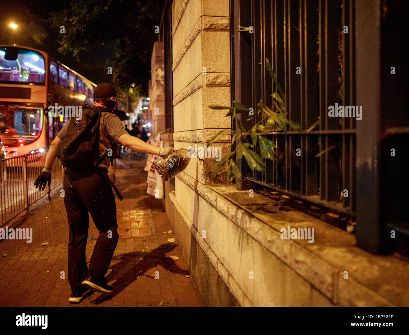 A man pours inflammable liquid outside a police station. Hundreds of people gather to protest a high school student shot with live round by police yesterday 1 Oct 2019. Some protesters later set the gate of a police station on fire in Hong Kong. Stock Photo