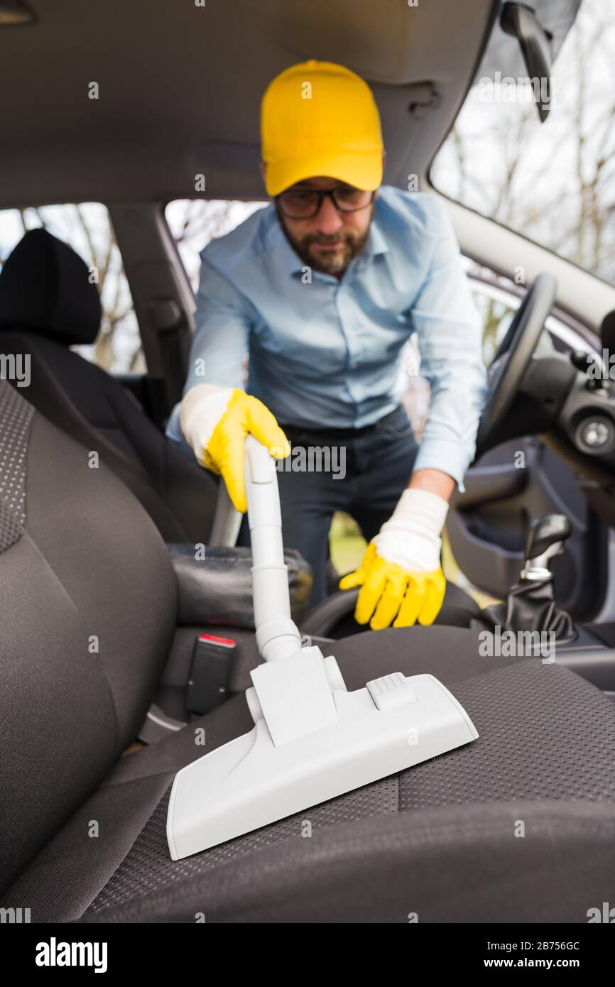 Male using professional steam vacuum for dirty car interior