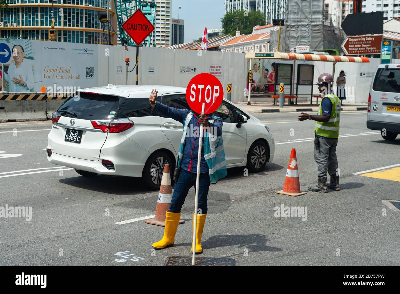 18042018-singapore-republic-of-singapore-asia-a-worker-uses-a-stop-sign-to-control-traffic-at-a-construction-site-in-chinatown-automated-translation-2B757PW.jpg