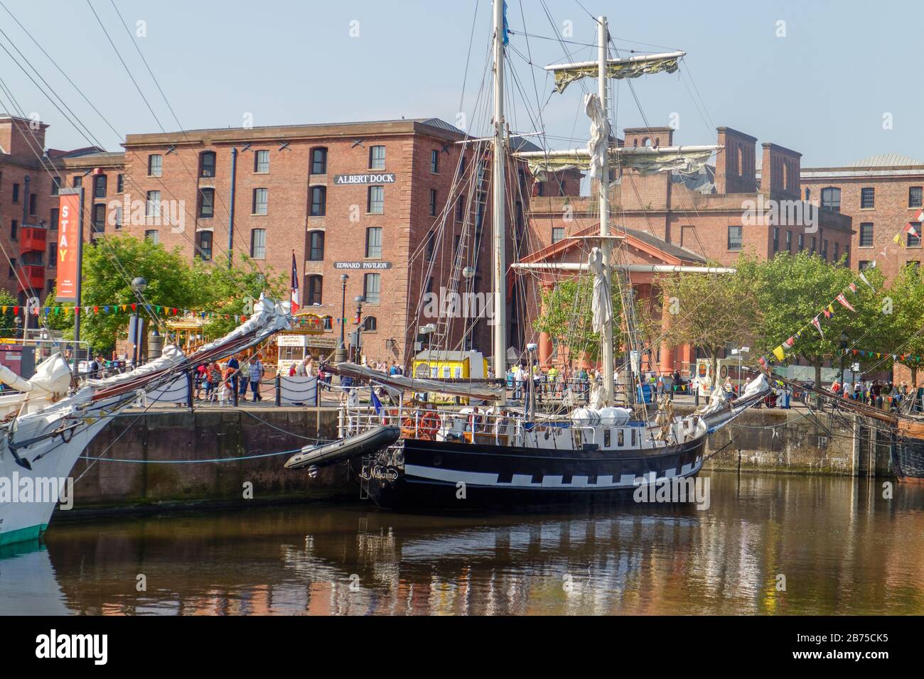 Tall ship La Mouine in Canning Dock at Liverpool waterfront, with the former warehouses of Royal Albert Dock in the background Stock Photo