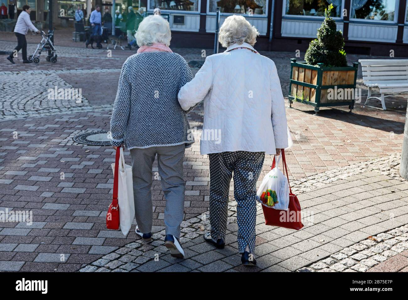 Two pensioners are walking arm in arm on 06.10.2018. In the background you can see a senior citizen with a walker. [automated translation] Stock Photo