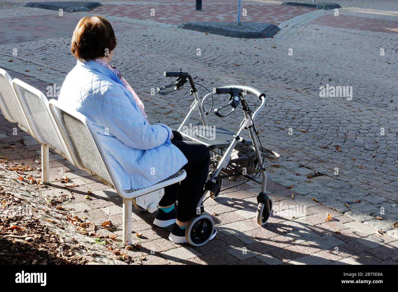 A pensioner sits on a bench on 06.10.2018, in front of her stands a walker [automated translation] Stock Photo