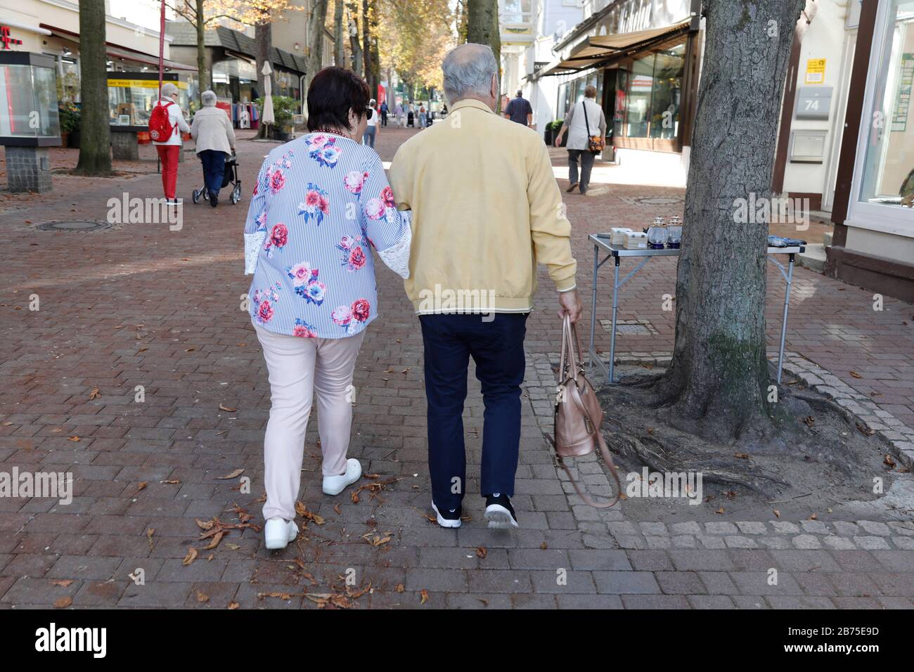 Arm in arm a pensioner couple walks through the shopping street of a