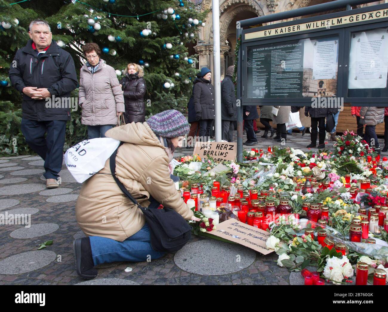 A woman is lighting a candle at the Gedaechtniskirche, where many people are laying flowers in memory of the victims of the terrorist attack on Breitscheidplatz. [automated translation] Stock Photo