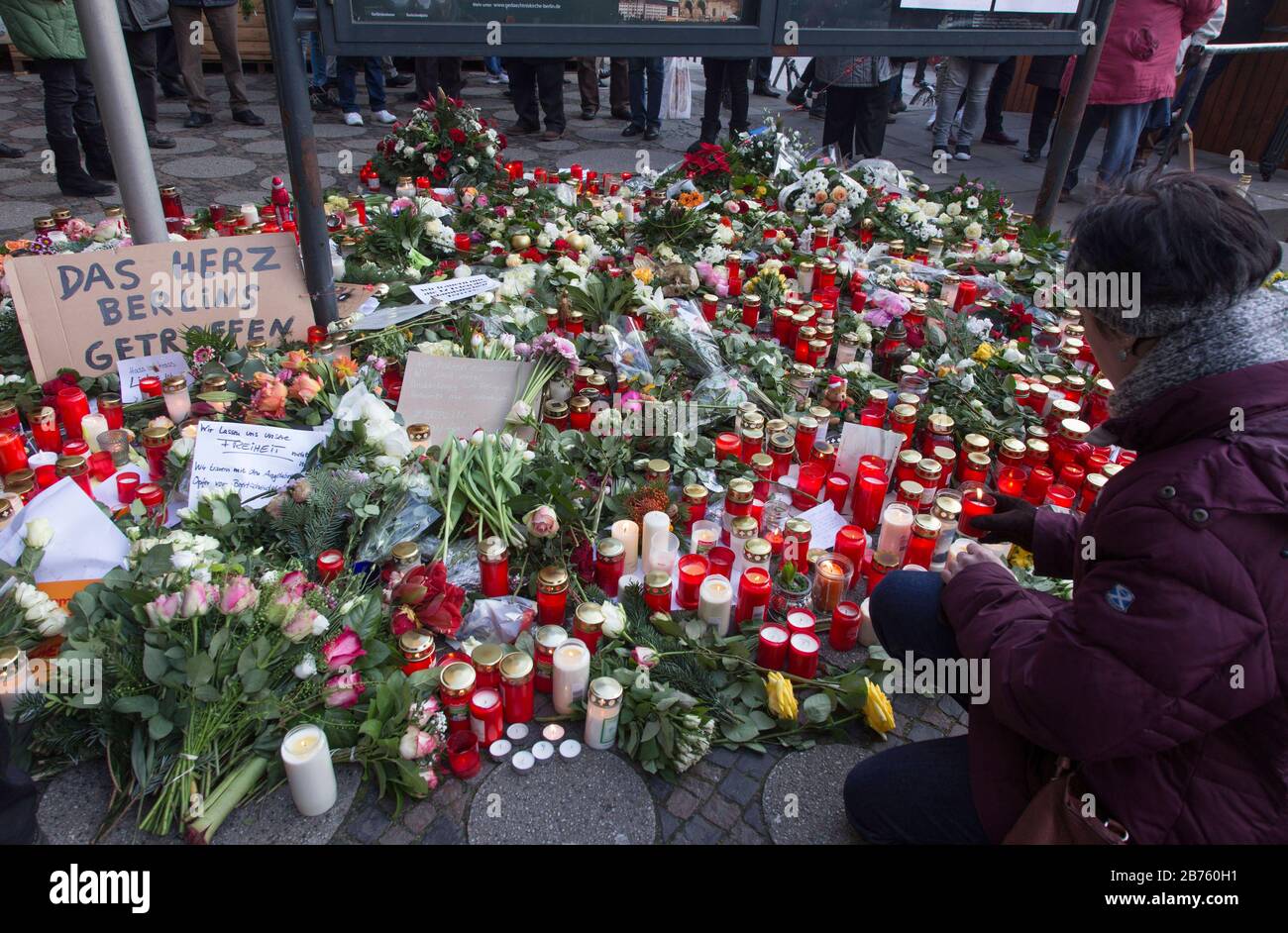 A woman is lighting a candle at the Gedaechtniskirche, where many people are laying flowers in memory of the victims of the terrorist attack on Breitscheidplatz. [automated translation] Stock Photo