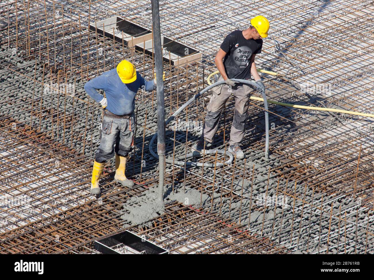 Construction workers filling concrete with a concrete pump at a