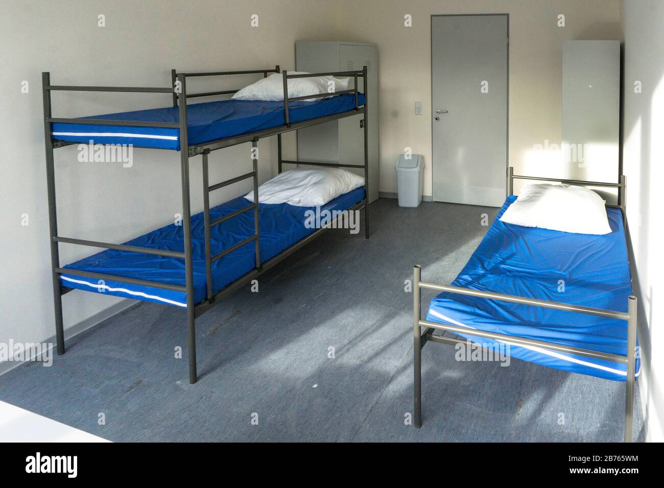 View into a newly furnished room for refugees in a first reception facility for asylum seekers. In the room there is a double bed ,a single bed and a wardrobe, on 05.12.2015 [automated translation] Stock Photo