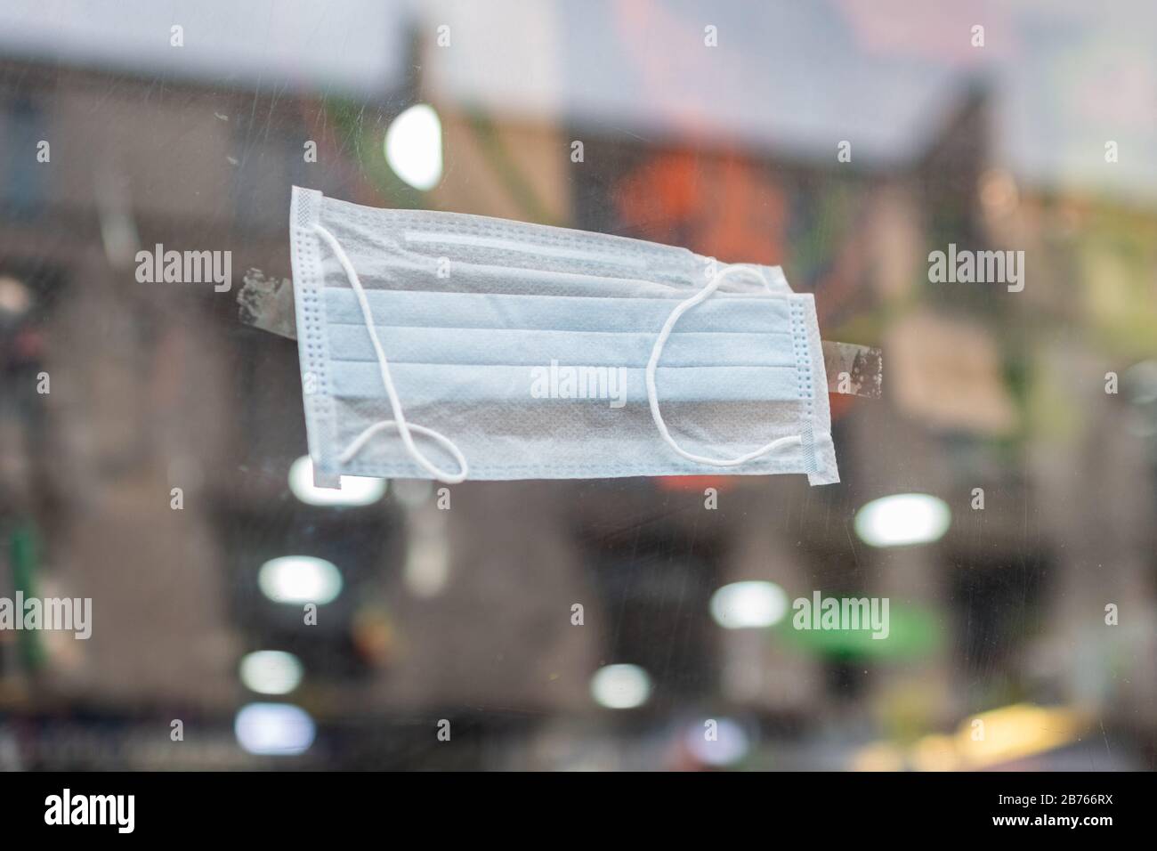 Face mask attached to shop window during the Coronavirus outbreak, Glasgow, Scotland, UK Stock Photo
