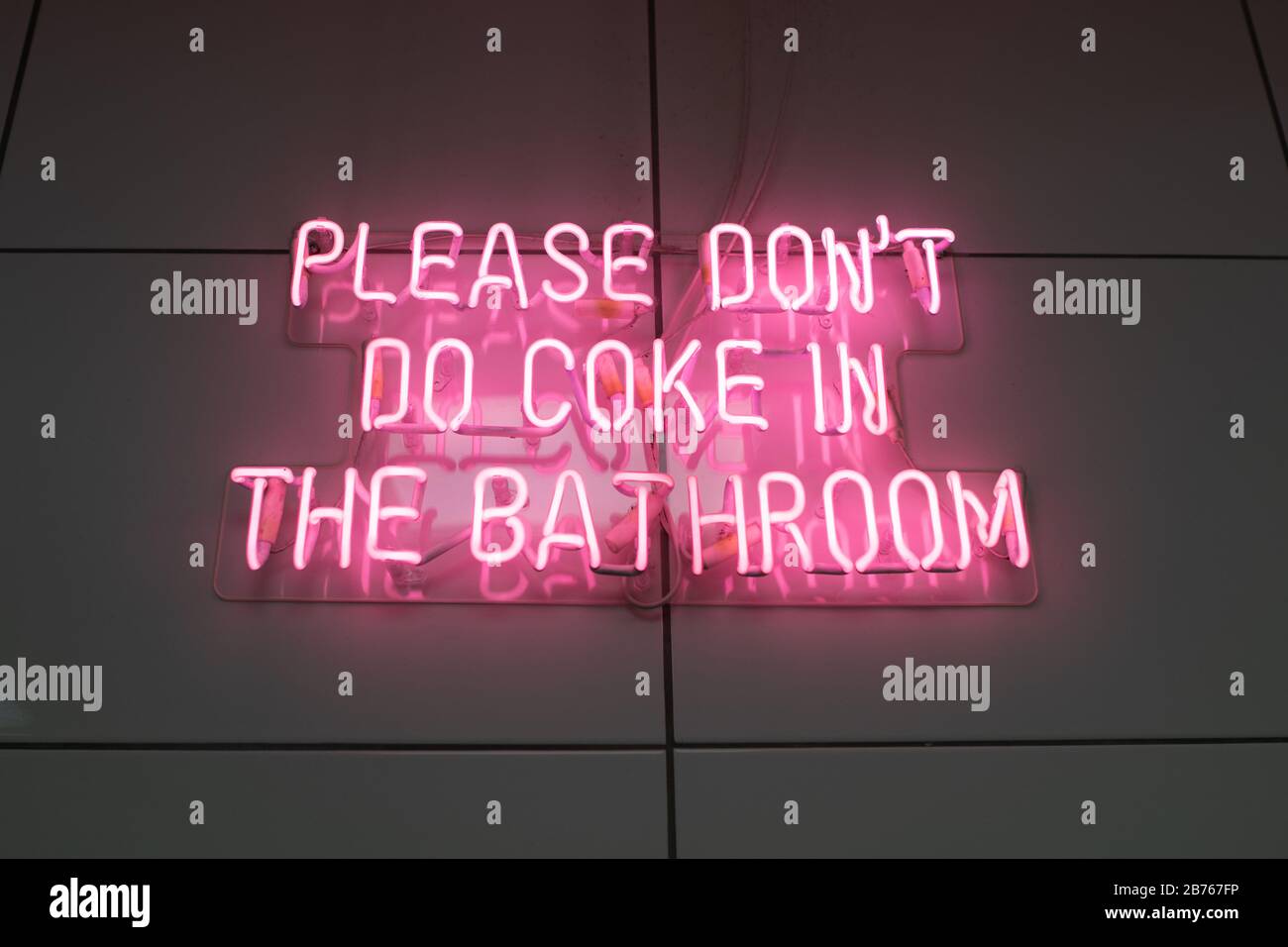 Please don't do coke in the bathroom pink neon sign Stock Photo