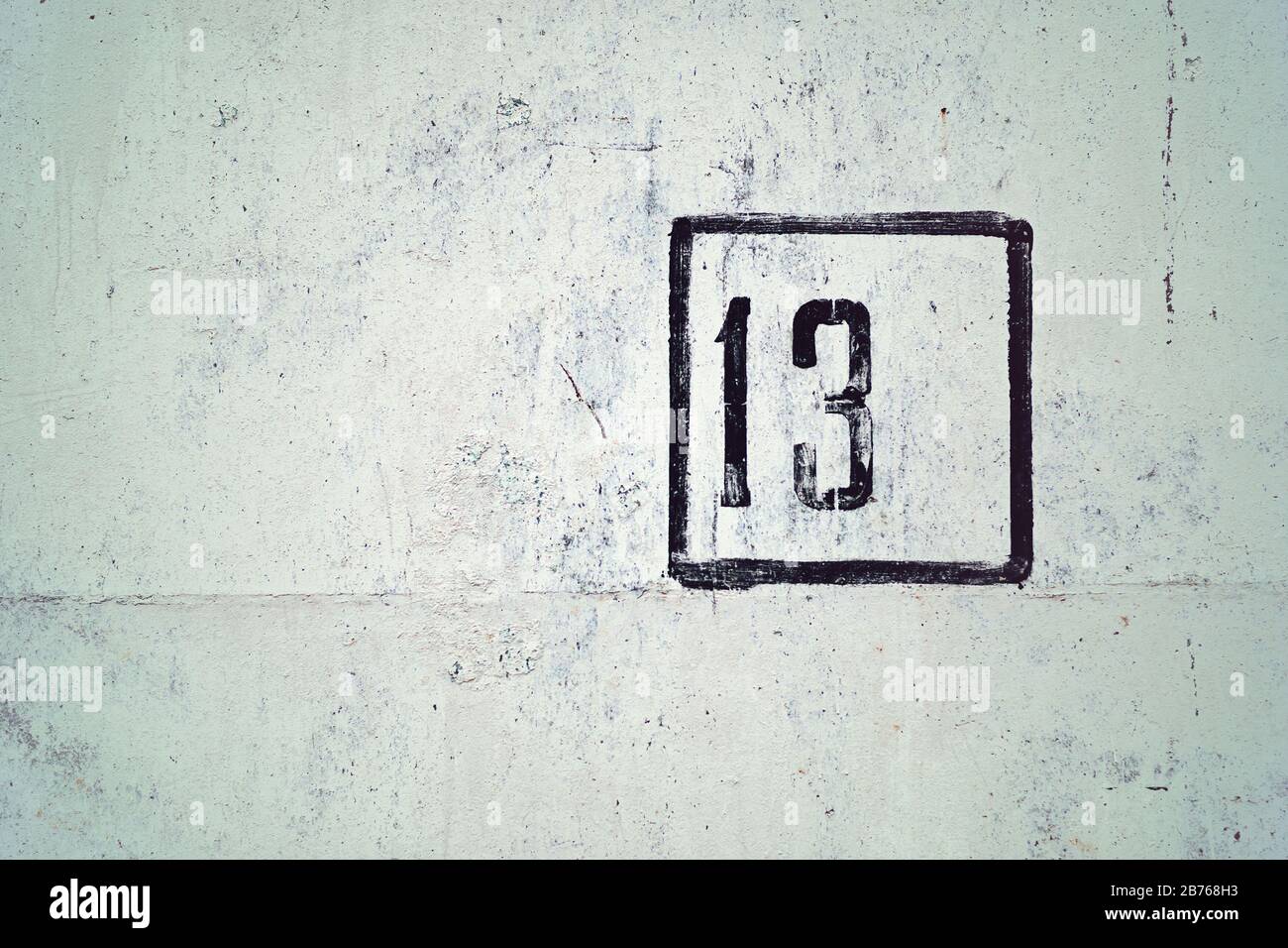 number 13 painted on white house wall Stock Photo