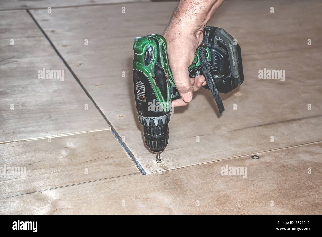 Carpenter screw screwdriver spin into a sheet of plywood. Repair floor Stock Photo Alamy
