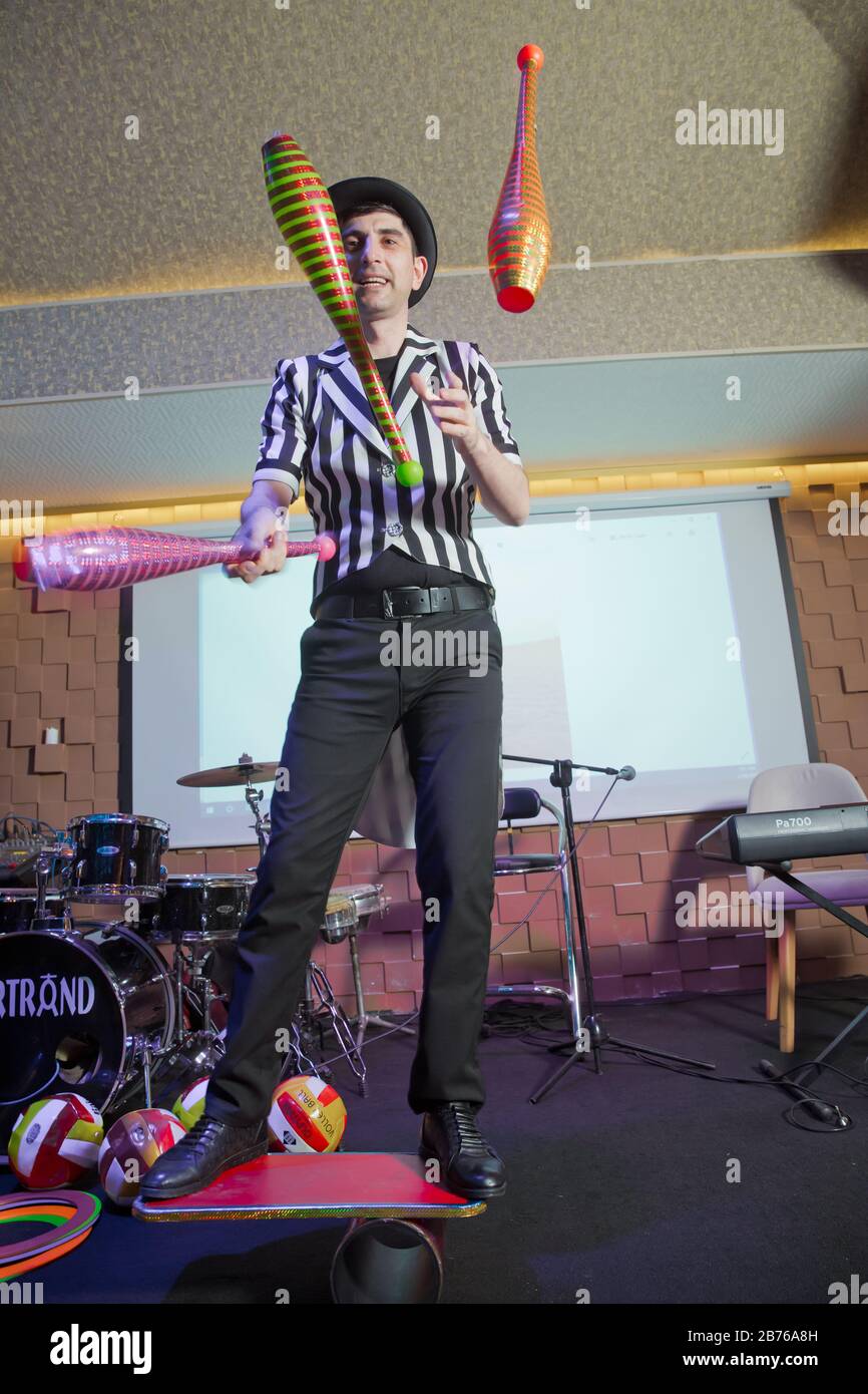 Man standing on top of cylinders and juggling glass bottles, one bottle
