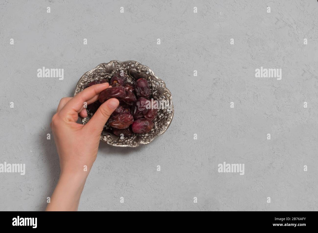 Woman hand holding dry date on neutral concrete background. Ramadan fasting concept. Top view with copy space Stock Photo