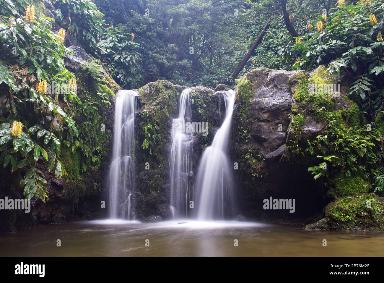 Natural waterfall surrounded by rocks and foliage at the Parque Natural da Ribeira dos Caldeirões, São Miguel island, Azores. Stock Photo