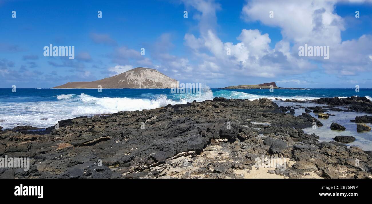 View of Rabbit Island from the jagged lava rock beach of Oahu's South Shore Stock Photo