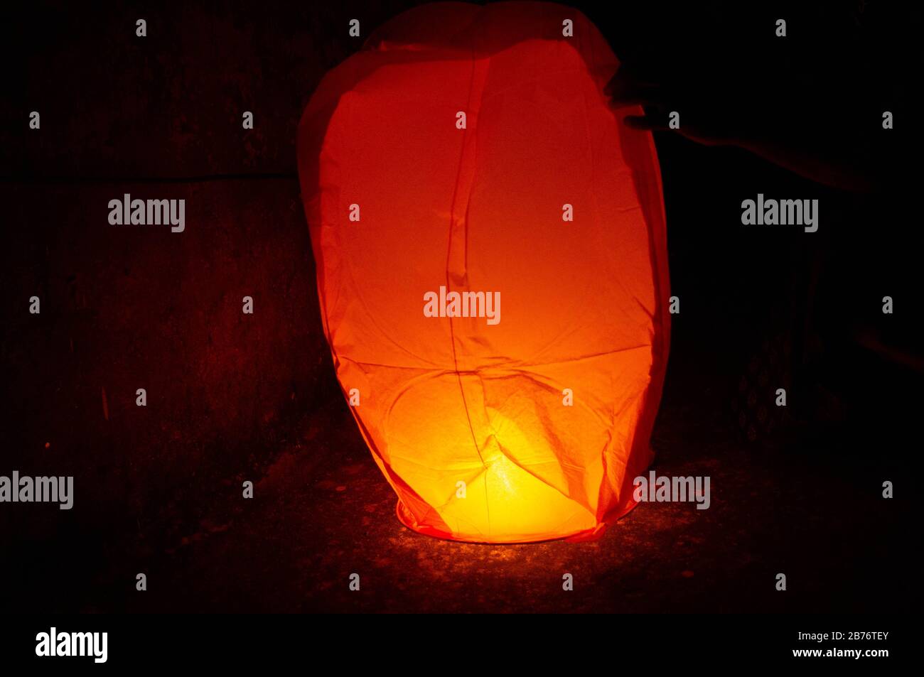 Jaipur India, Circa 2020 - Photograph of a Red Sky lantern with the flames showing clearly on the ground and waiting for it to lift off at night. This Stock Photo