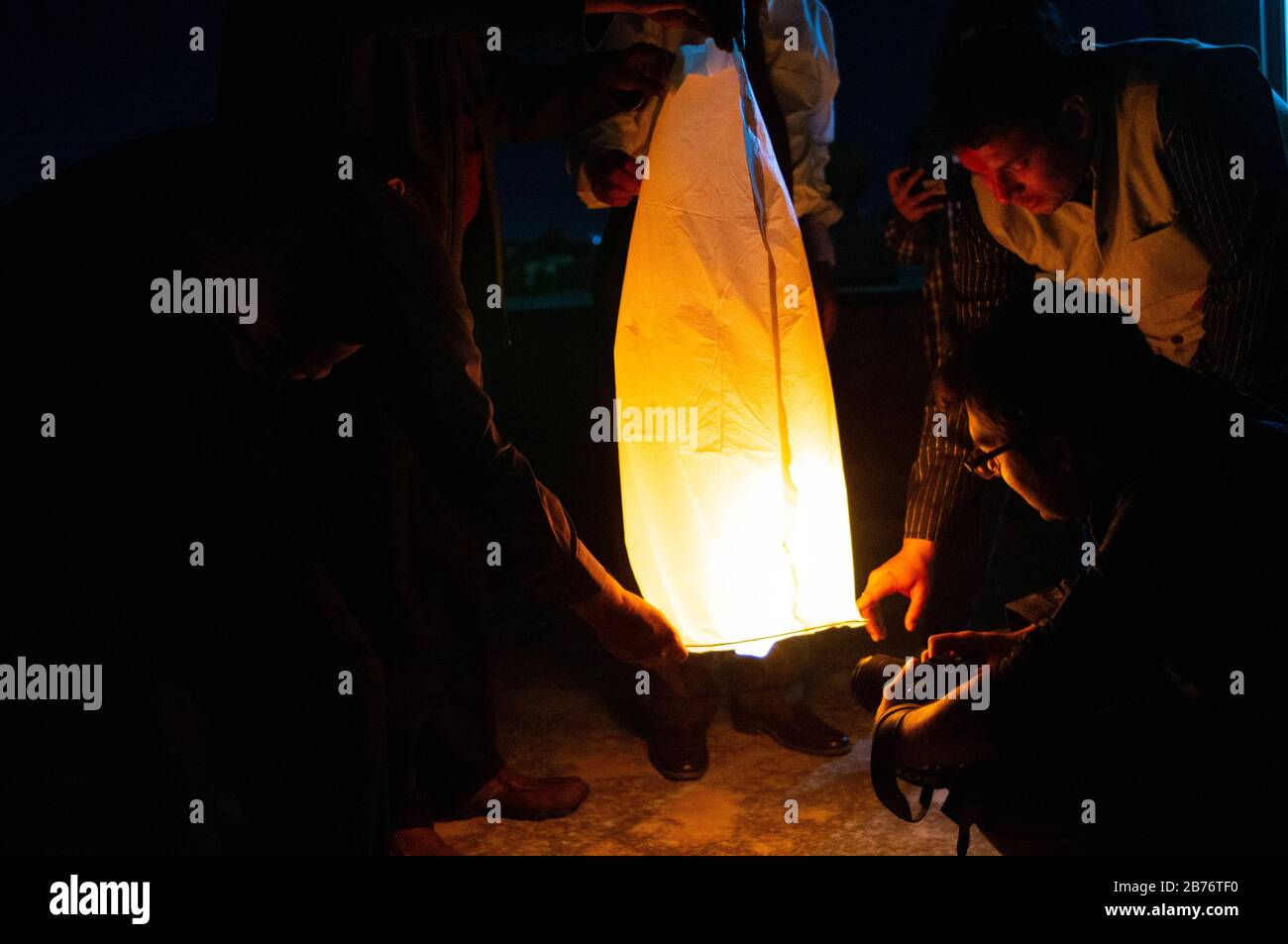 Jaipur India, Circa 2020 - Photograph of a yellow Sky lantern held by people and waiting for it to lift off. The flames are clearly visible in the pho Stock Photo