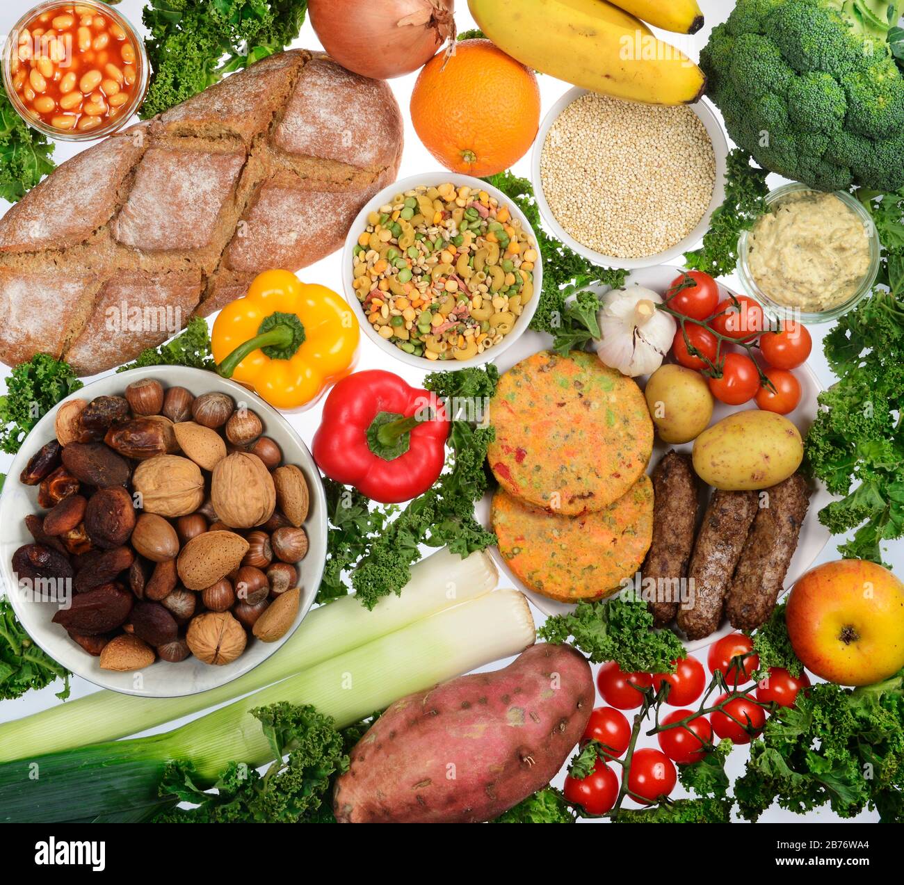 Vegan food, including bread, vegetables, fresh fruit, vegan burgers and sausages, hummus, quinoa, beans, peas, pulses, pasta, dried fruit and nuts. Stock Photo