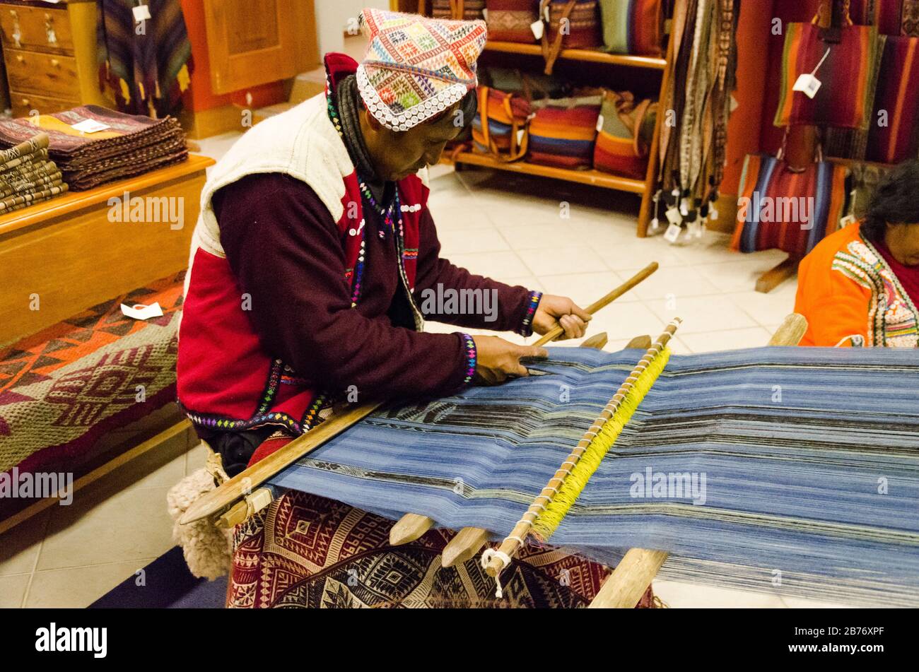 Cusco, Peru - January 22, 2017: A Peruvian man weaves a loom inside of a workshop, Cusco, Peru Stock Photo