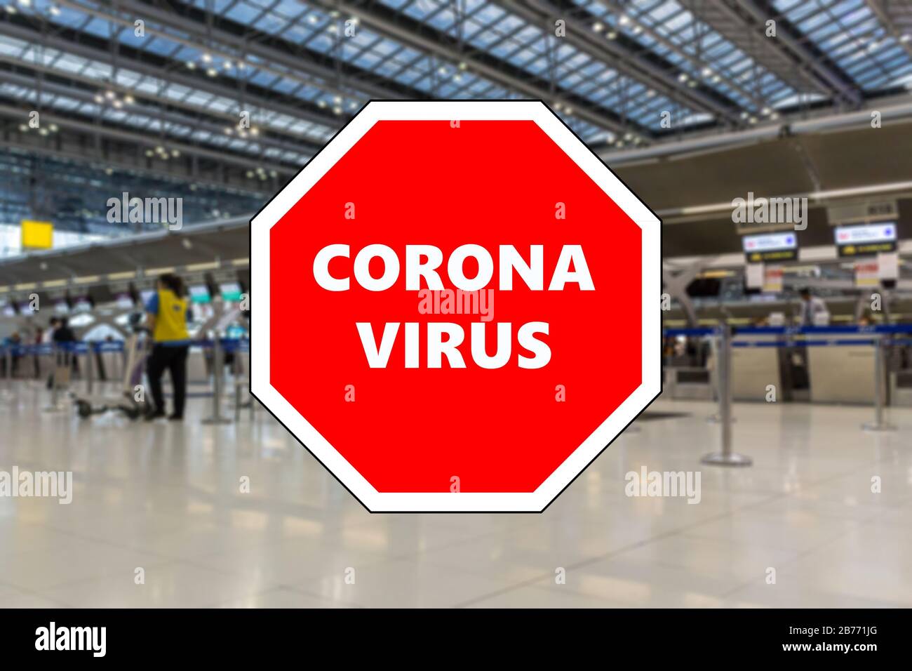 Stop sign displaying Coronavirus over a blurred photo of check in desks, Bangkok, Thailand Stock Photo