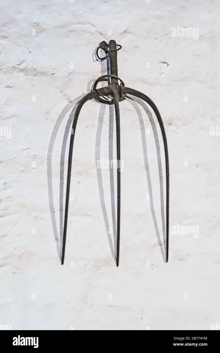 Pitchfork hanging on a white wall Stock Photo