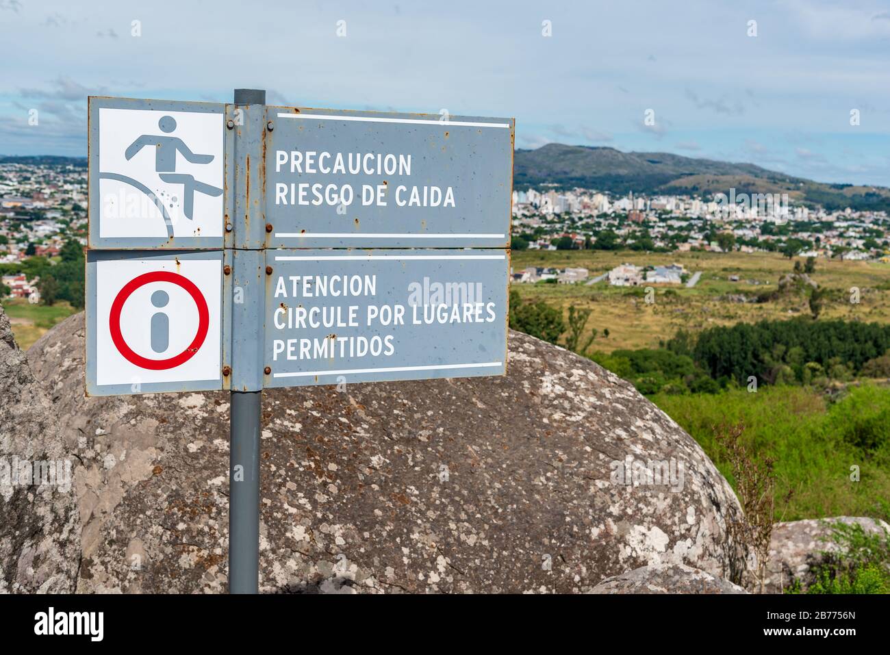 Warning signs of fall in spanish meaning 'Precaution risk of falling' and 'Attention circulate through allowed places', with a landscape of a city in Stock Photo