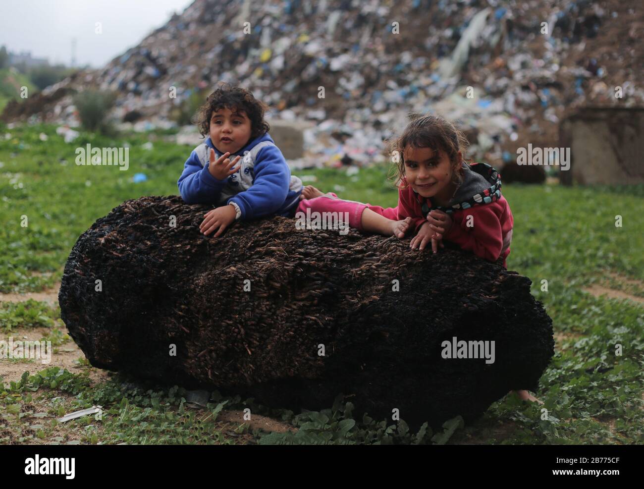 Gaza, Palestine. 13th Mar, 2020. Children play on a huge stone during a cold weather wave in the outskirts of the poor neighbourhood of Khan Yunis refugee camp. Credit: SOPA Images Limited/Alamy Live News Stock Photo