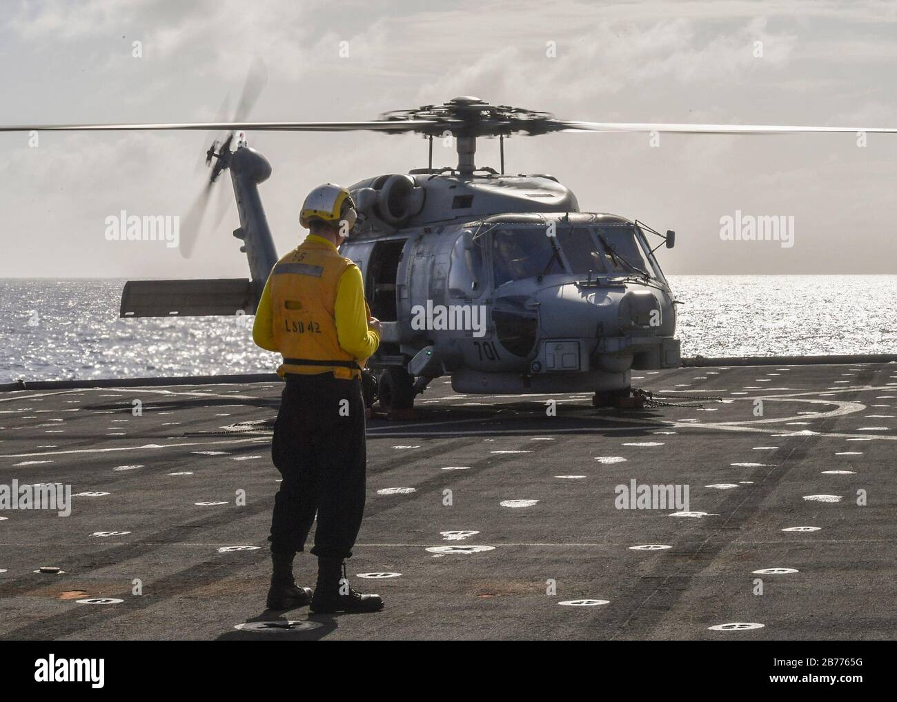 PHILIPPINE SEA (March 13, 2020) Boatswain's Mate 3rd Class Jack Erickson, from Lowell, Mass., observes an MH-60R SeaHawk helicopter assigned to the “Saberhawks” of Helicopter Maritime Strike Squadron (HSM) 77 on the flight deck of Whidbey Island-class dock landing ship USS Germantown (LSD 42) during flight operations. Germantown, part of America Expeditionary Strike Group, 31st Marine Expeditionary Unit team, is operating in the U.S. 7th Fleet area of operations to enhance interoperability with allies and partners and serves as a ready response force to defend peace and stability in the Indo-P Stock Photo