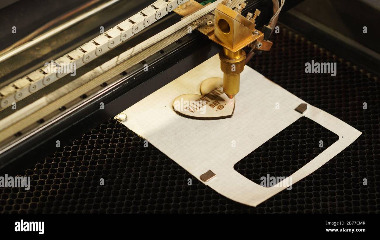 Laser cutting beam high precision on a plywood sheet. Modern technology of  wood cutting. laser cut wooden 3d symbol of valentine's day. Industrial  laser engraving. CNC laser. Masterclass, workshop Stock Photo -