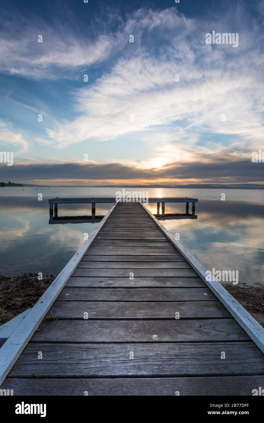 Sunset across lake Macquarie south of Newcastle featuring on of the wooden piers on the lake front. Lake Macquarie is Australia's largest saltwater la Stock Photo